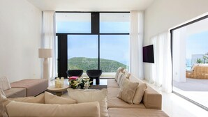 A modern living room with a large window, a sofa set, a small table with candles, and a TV. - Modern Villa in Santa Eulalia (Santa Eulalia del Rio)
