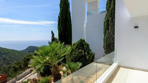 A modern building with a glass balcony overlooking a coastal landscape. - Modern Villa in Santa Eulalia (Santa Eulalia del Rio)