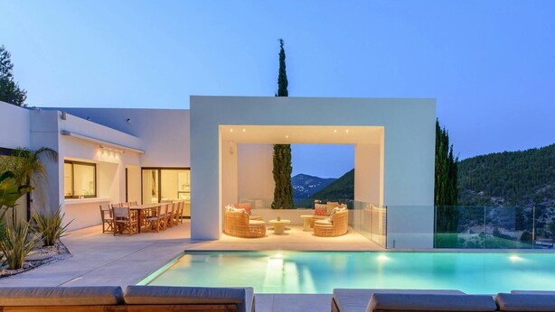 A modern outdoor pool area with lounge chairs and a dining setup. - Modern Villa in Santa Eulalia (Santa Eulalia del Rio)