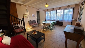 A cozy living room with a staircase, a dining area, and large windows. - Spacious house near the beach (Arcachon)