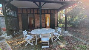 A covered patio with a round table and four white chairs. - Spacious house near the beach (Arcachon)