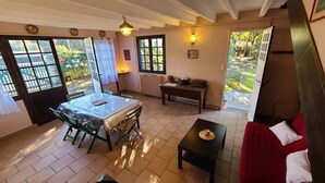 A cozy room with a dining table, chairs, a sofa, and a small table with a candle. There are windows and a door leading outside. - Spacious house near the beach (Arcachon)