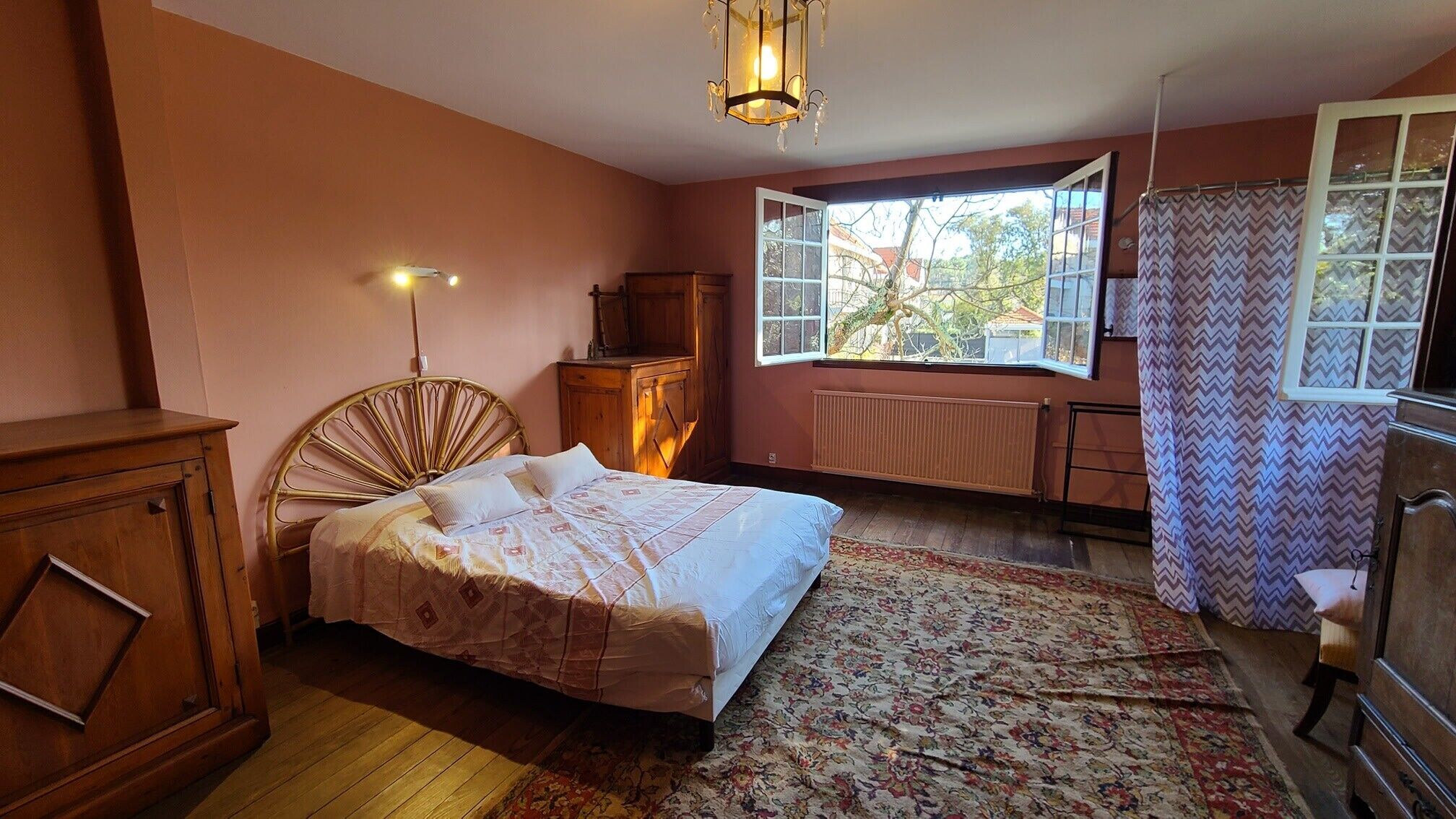 A bedroom with a bed, wooden furniture, a window, and a radiator.