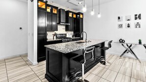 A modern kitchen with dark cabinetry, a granite countertop, and a central island.
