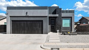 A modern two-story house with a garage, a large window, and a stone pillar.