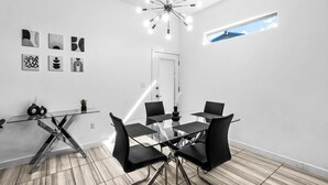 A modern meeting room with a glass table, black chairs, and abstract wall art.