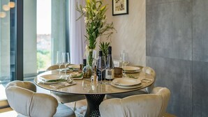 A round dining table with six chairs, a vase with flowers, wine glasses, and a bottle of wine. - Apartment Leonarda (Zadar)