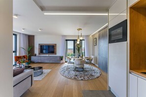 A modern living room with a TV, seating, and a dining area with a round table. - Apartment Leonarda (Zadar)