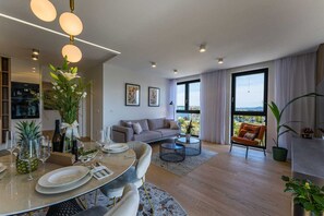 A modern living room with a dining area, a sofa, a coffee table, and a balcony with a view. - Apartment Leonarda (Zadar)