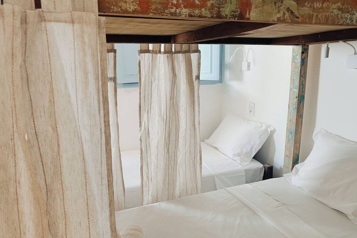 Une chambre rustique avec deux lits, des poutres en bois et une fenêtre avec des rideaux.