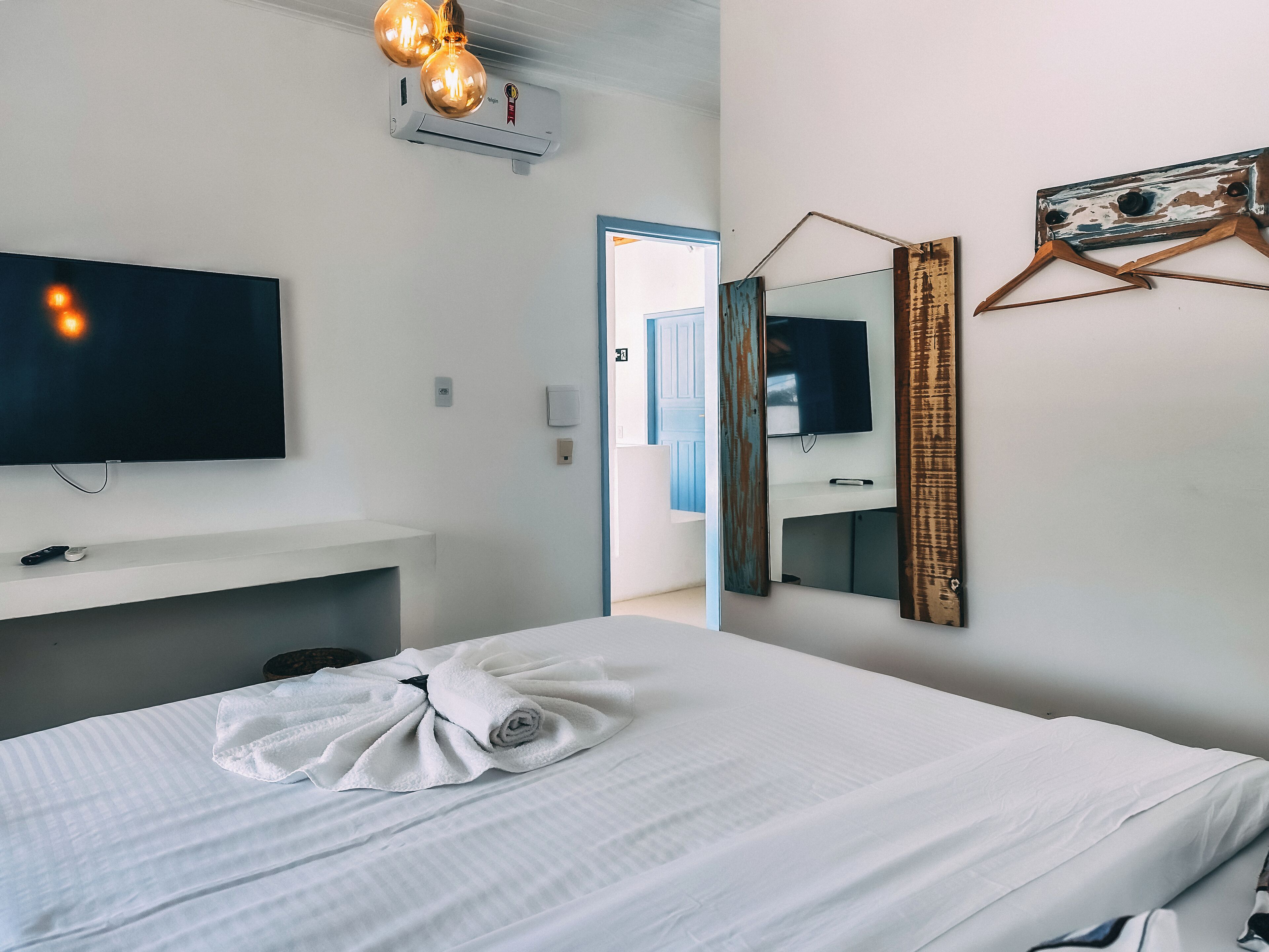 Ein Hotelzimmer mit Bett, Fernseher, Spiegel und einer Tür zu einem Badezimmer.