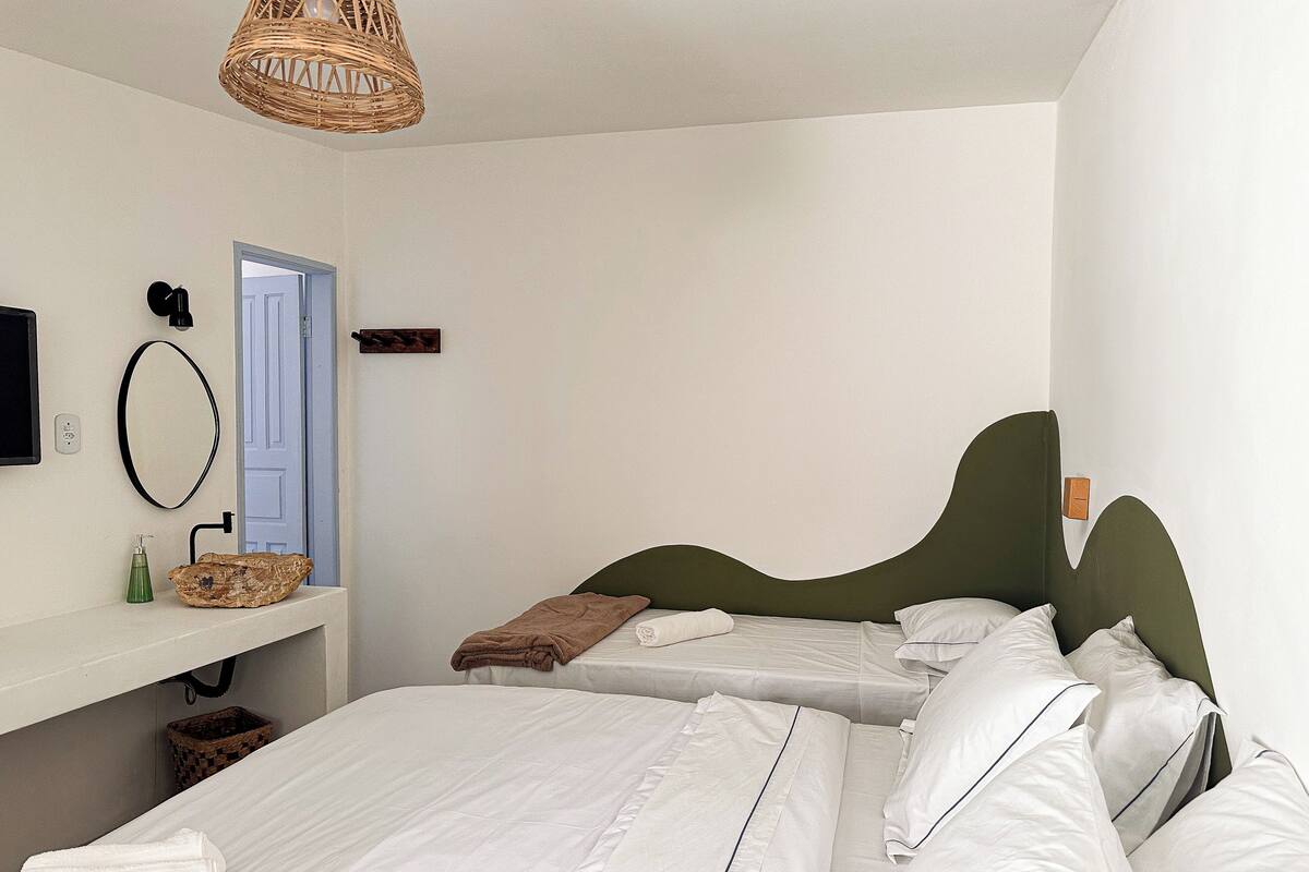 Une chambre avec deux lits, une table de chevet, un miroir et un luminaire suspendu.