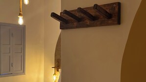 A hotel room with a bed, a wooden wall-mounted towel rack, a hanging light fixture, and a door. - Vilab  (Porto Seguro)