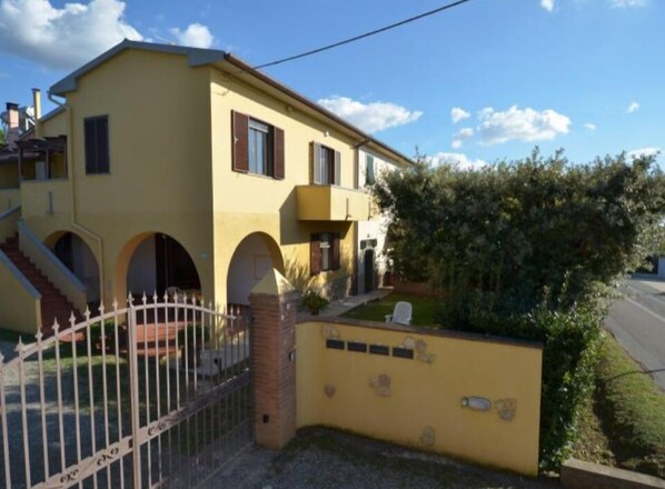 Stunning two-story residence with a central entrance, arched doorways, and a charming garden area.
