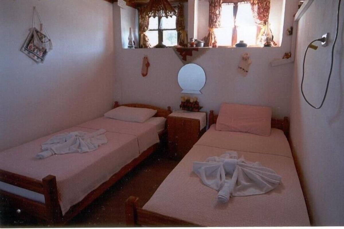 Ein kleines, gemütliches Schlafzimmer mit zwei Einzelbetten, einem kleinen Tisch und einem Spiegel.