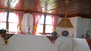 A bedroom with a wooden ceiling, a bed with pink and white bedding, a bedside table with a mirror, and a window with curtains. - Vome (Ortaca)