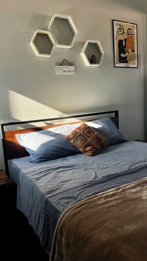 A bedroom with a bed, a pillow, and wall decorations including hexagonal frames and a framed picture. - Cozy & Chic 2BR Loft on 18th St in Chicago (Chicago)