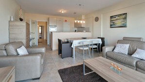 Een moderne woonkamer met een bank, een salontafel en een eethoek met een tafel en stoelen.