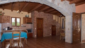 Una cocina rústica con pared de ladrillo, vigas de madera y una zona de comedor con mesa y sillas.