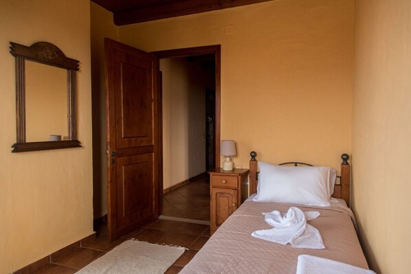 Un dormitorio con una cama, una mesita de noche, una lámpara, un armario de madera y un espejo.