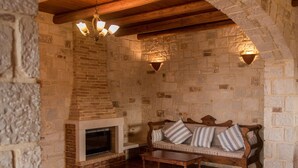 Una habitación de paredes de piedra con chimenea, un banco de madera y un sofá acolchado.