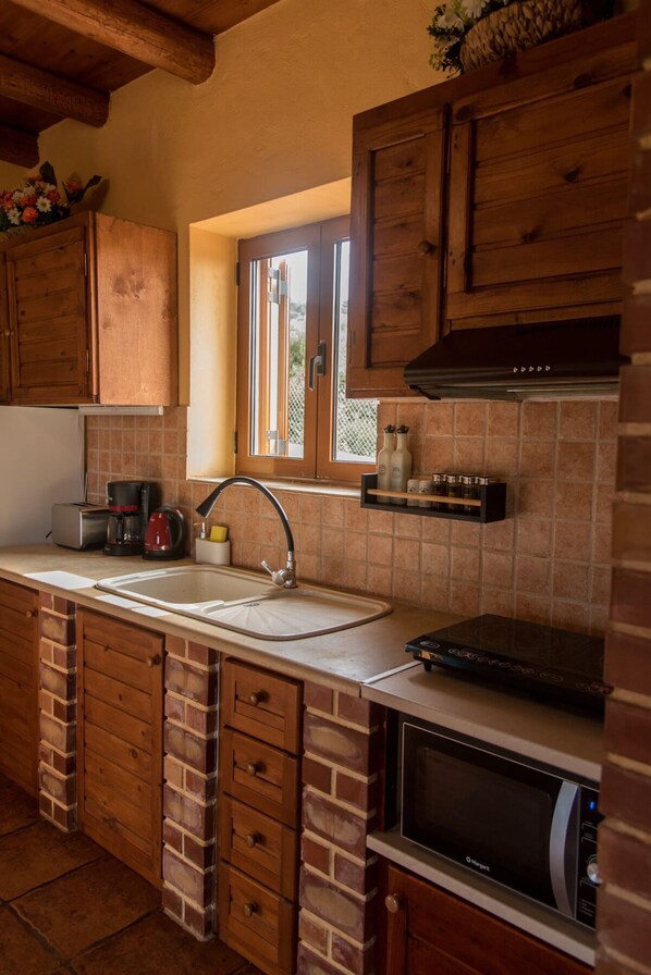 A kitchen with wooden cabinets, a built-in microwave, a sink, and a window with a view.