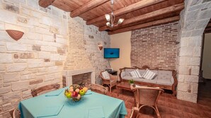 Un comedor con pared de piedra, techo de madera y una mesa con fruteros.