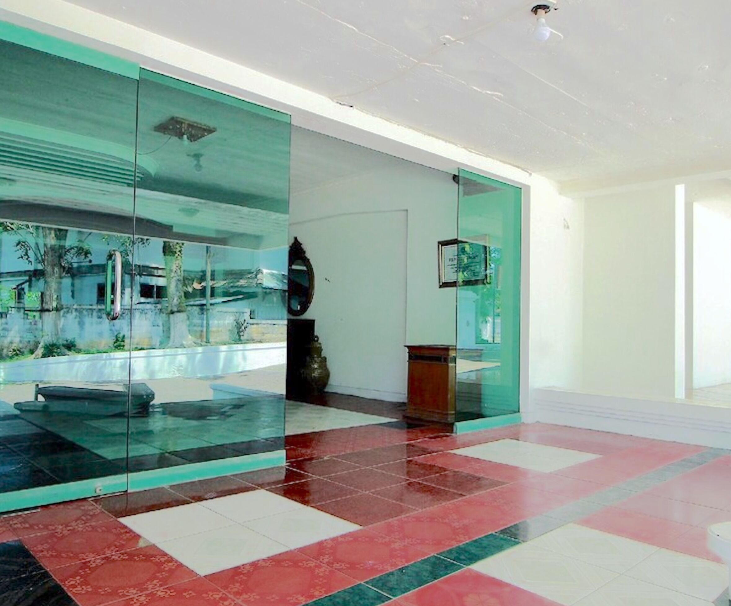 A modern lobby with a glass partition, a tiled floor, and a statue.