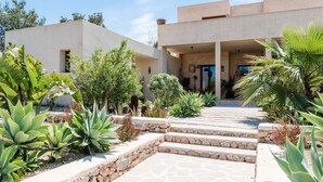 A modern building with a stone pathway leading to a covered entrance. - Stunning Villa With Gardens (Sant Josep de sa Talaia)