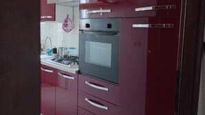 Une cuisine avec des meubles de couleur rouge foncé, un four en acier inoxydable et un four à micro-ondes.