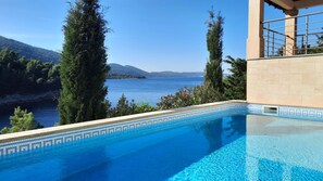 Relax by the serene pool overlooking a tranquil lake and distant mountains.