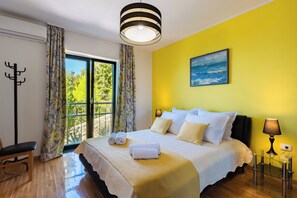 Une chambre d’hôtel avec un grand lit, une vue sur la verdure par la fenêtre et un tableau accroché au mur.