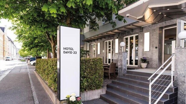 L'ingresso di un hotel con un cartello che riporta 'HOTEL DAVID 22', una scalinata e un marciapiede lastricato.