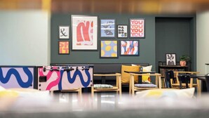 Un interno moderno con angolo salotto, opere d'arte alle pareti e una pianta su un tavolo.