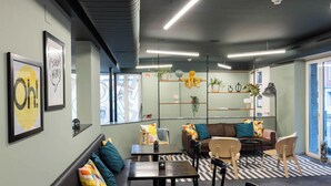 Un ambiente moderno con un divano, tavoli e sedie disposti per sedersi.