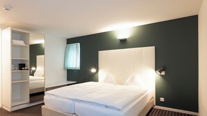Una camera d'albergo con un letto grande, un armadio, uno specchio e un comodino.