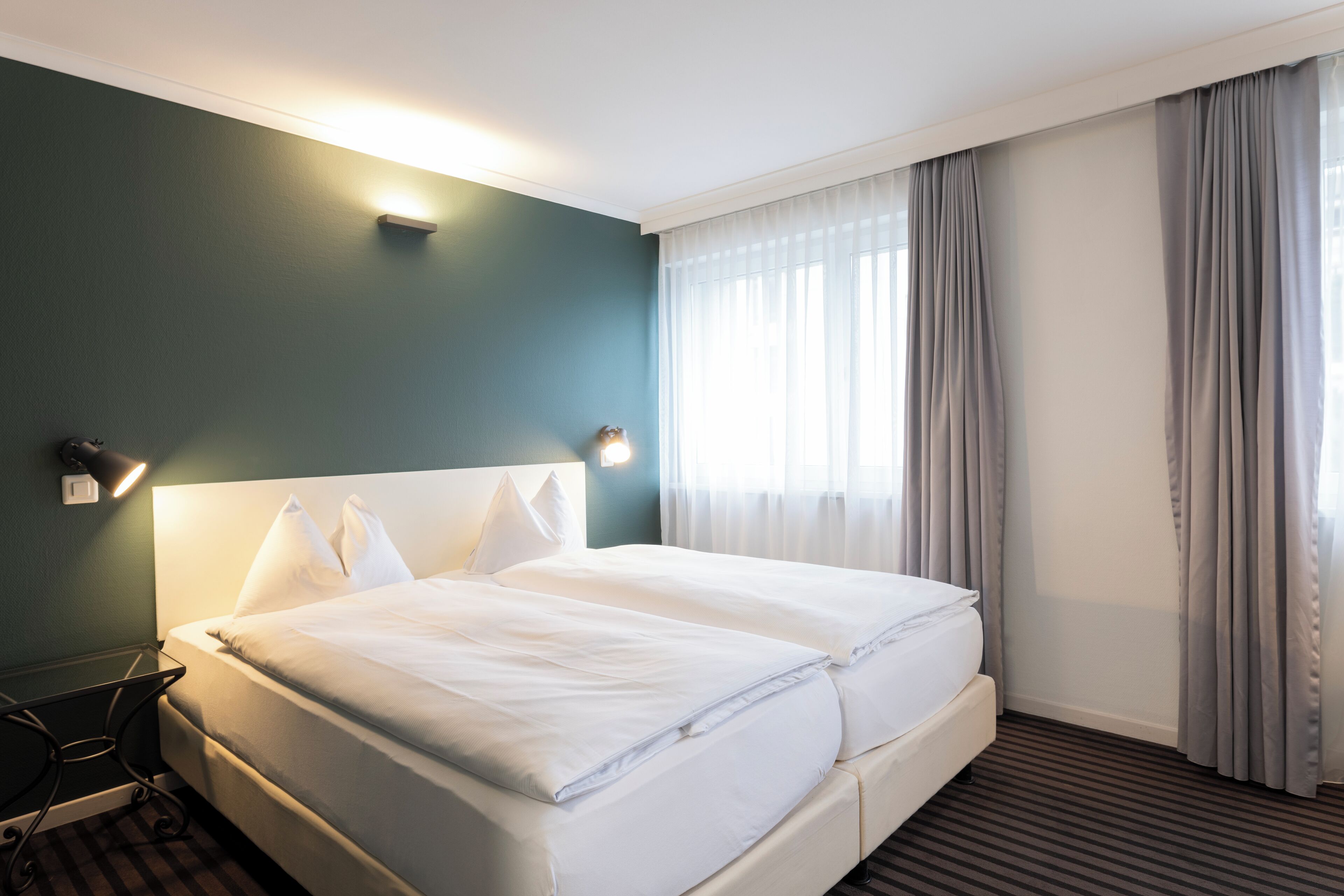 Una habitación de hotel con una cama grande, una mesita de noche y una lámpara.