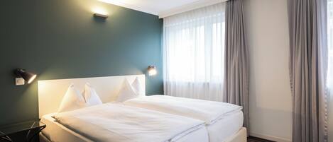 Una habitación de hotel con una cama grande, una mesita de noche y una lámpara.