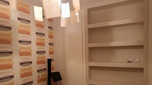 A bedroom with a bed, a wall with circular cutouts, and built-in shelves. - St. Peter's  (Roma)