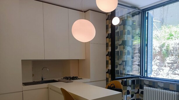 A modern kitchen with a central island, a window with a view, and a radiator. - St. Peter's  (Roma)