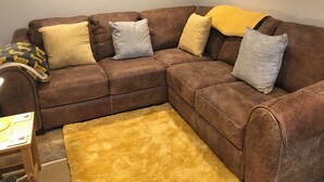 A brown leather sectional sofa with multiple cushions in a living room. - Idyllic cottage with private hot tub in picturesque village in the Peak District (Brassington, Matlock)