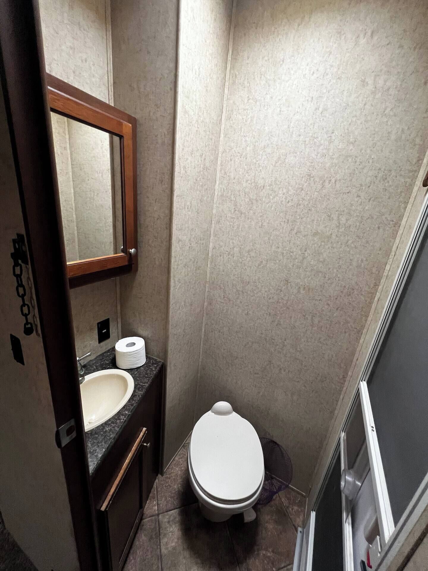 Un baño pequeño con lavamanos, espejo, inodoro y ducha.