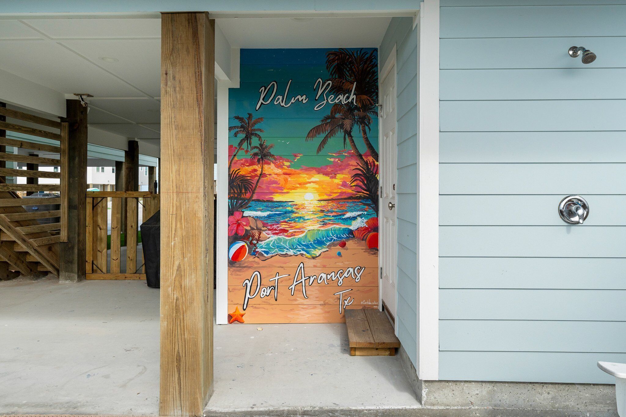 A beach-themed mural on a building's exterior wall with palm trees, a sunset, and the text "Palm Beach Part Aransas Tx."