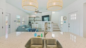 Une cuisine moderne dotée d’un grand îlot central, de deux éviers et d’un ventilateur de plafond.