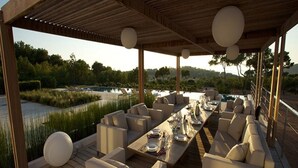 An outdoor dining area with a long table set for six, surrounded by cushioned seating. - Gorgeous Villa With Views (Sant Josep de sa Talaia)