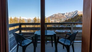 A balcony with a table and chairs, offering a view of snow-capped mountains and trees. - 40m from ski slopes, 1st floor, fitness, swimming pool, sauna, balcony, tv, ski locker, 35m² (Les Orres)