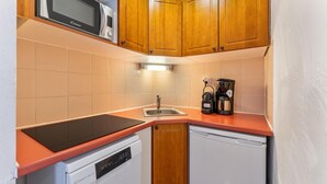 A compact kitchen with wooden cabinets, a microwave, a coffee maker, and a dishwasher. - 40m from ski slopes, 1st floor, fitness, swimming pool, sauna, balcony, tv, ski locker, 35m² (Les Orres)