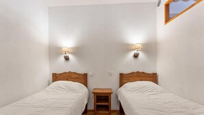A small, clean room with two single beds, a wooden nightstand, and wall-mounted lamps. - 40m from ski slopes, 1st floor, fitness, swimming pool, sauna, balcony, tv, ski locker, 35m² (Les Orres)