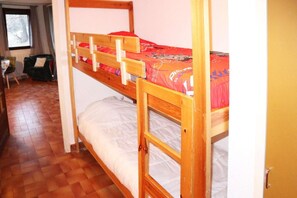 A bunk bed room with a wooden frame, a red mattress, and a white mattress. There is a chair and a window in the room. - 50m from ski slopes, 1st floor, 20m², Les Orres (Les Orres)