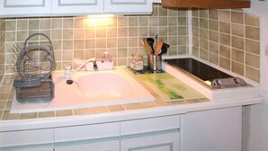 A kitchen with a sink, a stove, and a utensil holder.